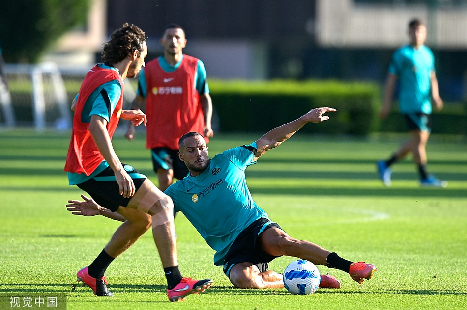 一位教练组成员正拿着战术板，向场上的球员们面授机宜，球员们围拢在他身边，神情认真，聆听着战术部署。