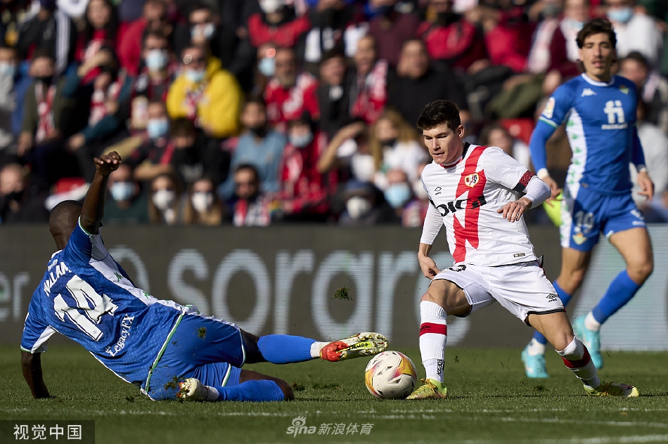 贝蒂斯球员激情滑跪庆祝扳平进球，身后是失望的巴列卡诺后卫与漫天飞舞的草屑。
