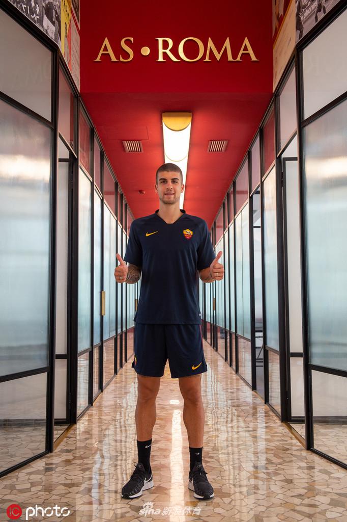 曼奇尼手持罗马围巾站在看台上，背景是罗马的训练基地，他的微笑充满感染力，仿佛在向未来球迷承诺自己的忠诚与拼搏。