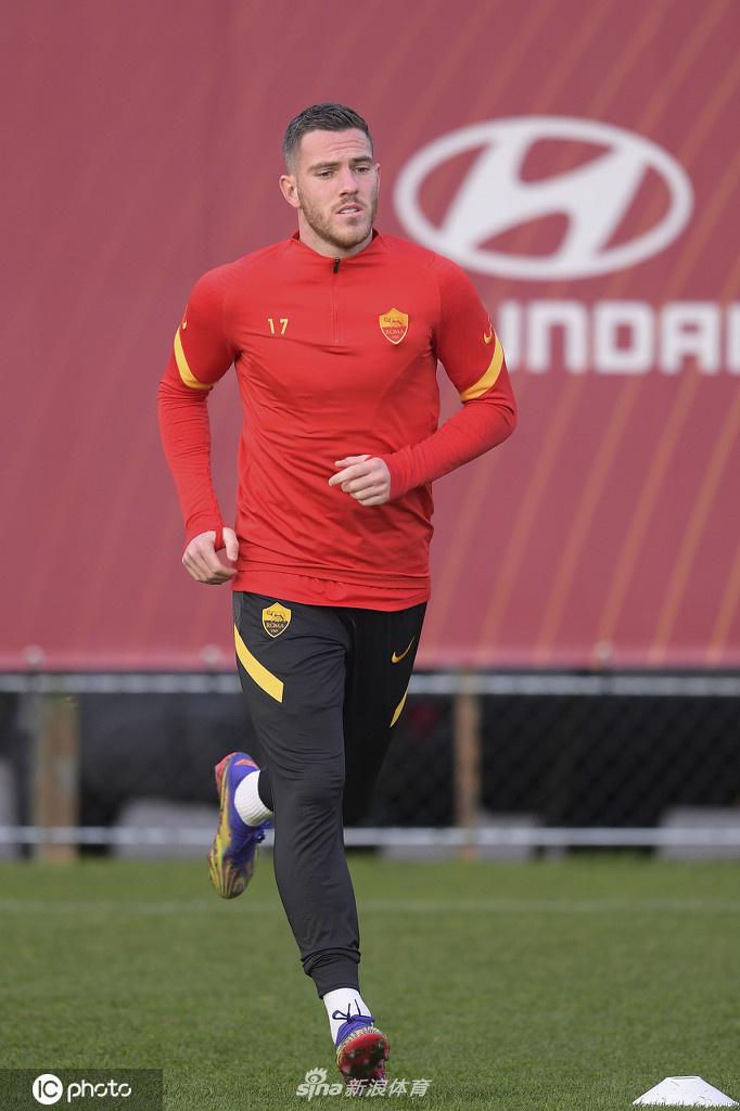 一位罗马球员正在进行高强度的盘带训练，皮球仿佛粘在他的脚下，他的眼神无比坚定，汗水在冬日阳光下闪闪发光。