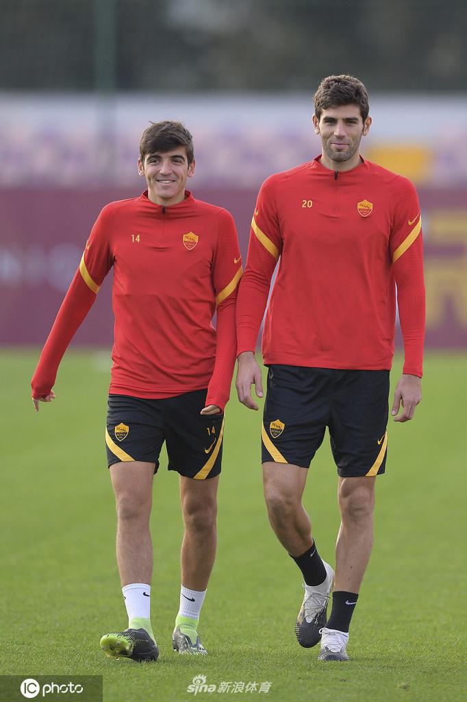 训练间隙，两位罗马队友在场边交流，一人手指球场方向，似乎在讨论战术细节，默契的团队氛围跃然纸上。