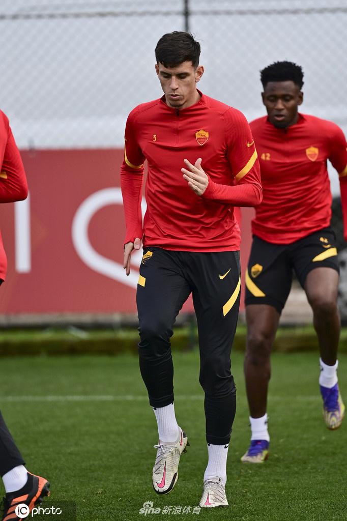 特写镜头中，罗马中场球员韦勒图正低头专注地调整自己的球袜和护腿板，身后的训练设施虚化成背景，这份细致入微的准备，显示出职业球员对比赛的严谨态度。