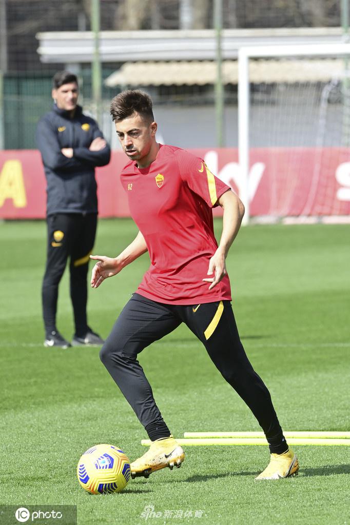 门将教练正在对罗马的守门员进行一对一的指导。训练器材散落一旁，守门员双手撑膝，大口喘着粗气，专注地聆听着教练的战术布置，他身后的球门在空旷的球场中显得格外巨大。