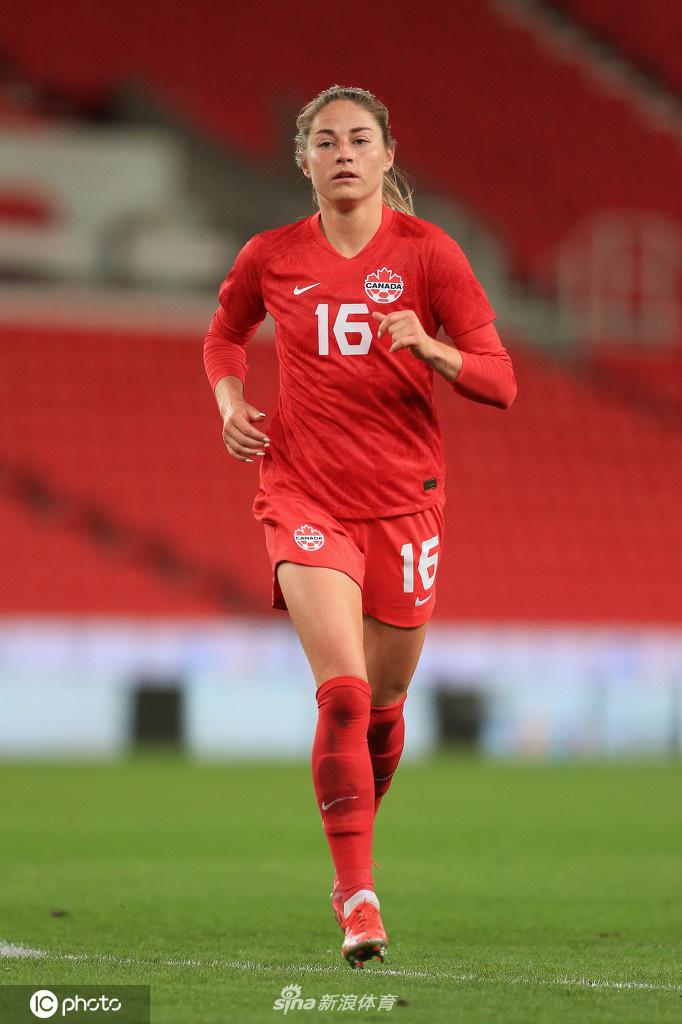 在激烈的身体对抗中，一名英格兰与一名加拿大球员为争夺球权人仰马翻，皮球被压在身下，场边的边裁全神贯注，随时准备做出判罚，比赛的紧张气氛可见一斑。