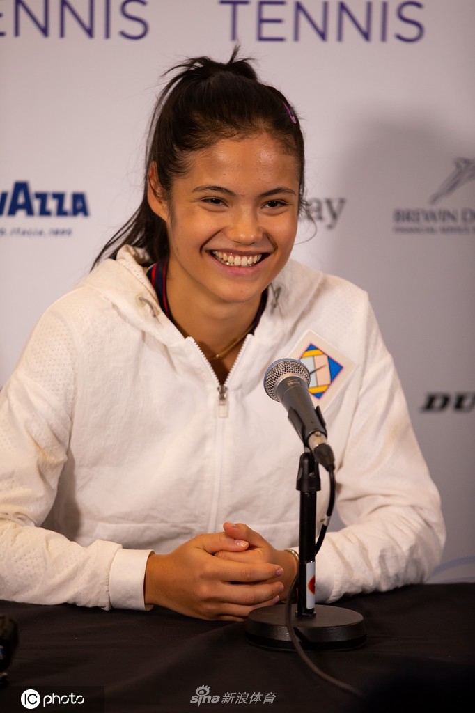 拉杜卡努在发布会上整理秀发，眼神望向远方，似乎在憧憬着即将到来的二零二二赛季。背景的虚化让她的侧颜轮廓更加鲜明，透出一股年轻运动员特有的专注与坚定。