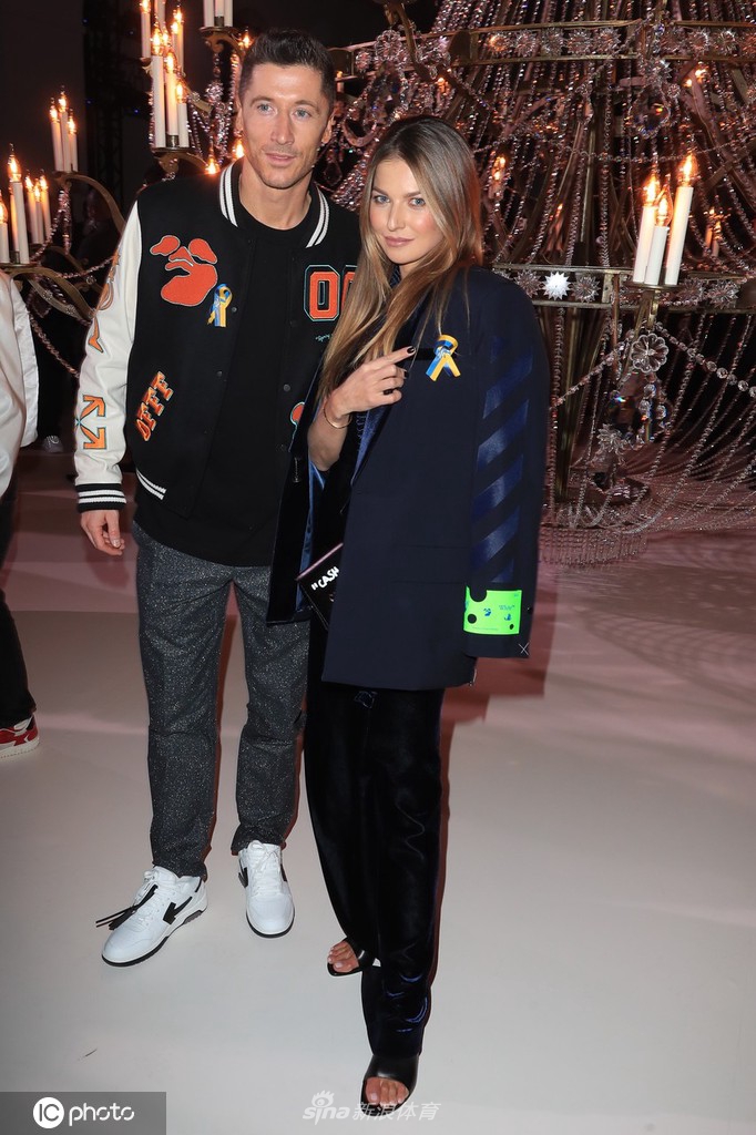 安娜为莱万整理衣领，莱万微微弯腰配合，这个日常化的动作在时装周的背景下显得格外亲密与自然。