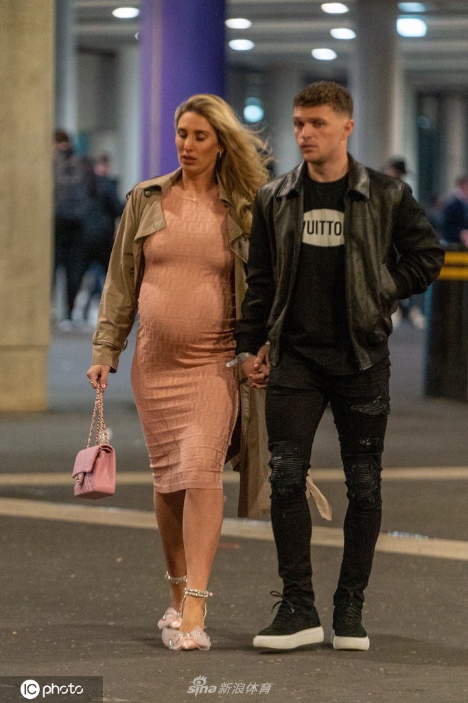 特里皮尔的女友笑容灿烂地看向镜头，她身处于激动人心的比赛氛围中，神情愉悦而放松。