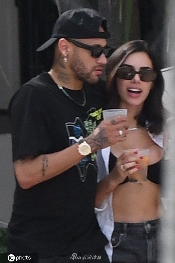 布鲁娜身穿黑色泳衣，戴着时尚墨镜，自信地漫步在沙滩上，展现了迷人的超模范儿。