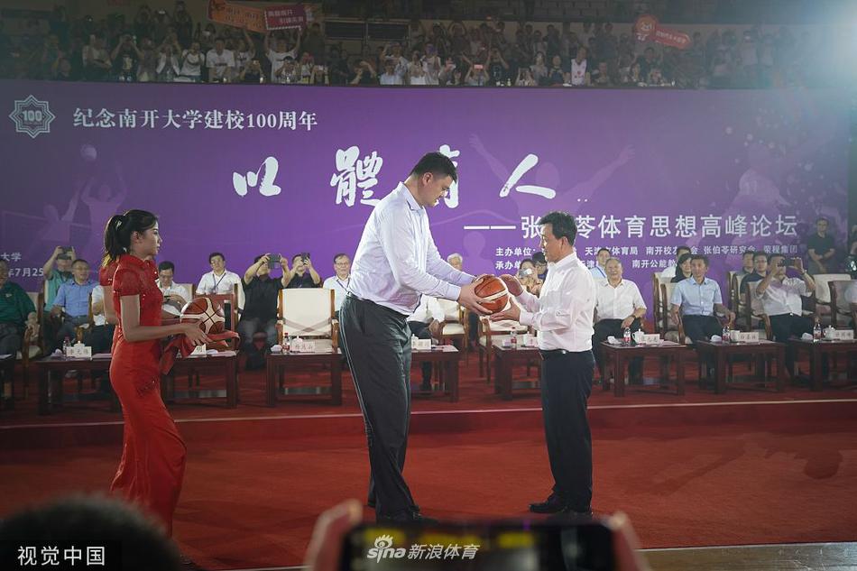 姚明弯下高大的身躯，双手将一只签满国家队队员名字的篮球递给南开大学的学生代表，鼓励他们热爱运动、以体育人。