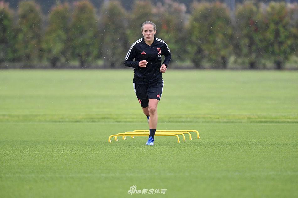 尤文图斯女足的训练中，一位球员进行高强度跑动，身后的维诺沃基地建筑在夕阳下显得宁静而坚实，见证着这支队伍的每一次冲刺与成长。