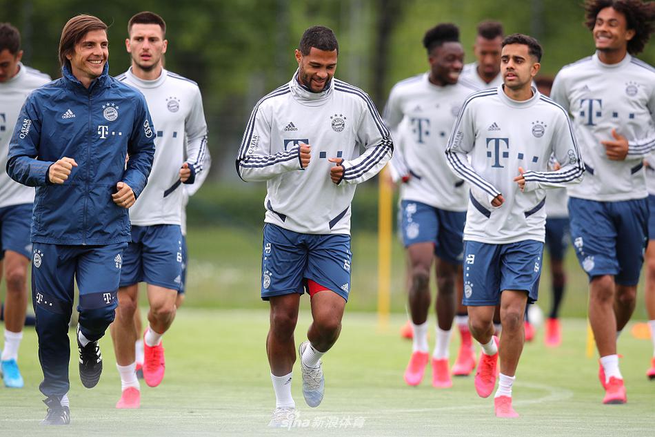 主帅汉斯·弗里克双手叉腰站在场边，目光如炬地注视着场上的一切，他的倒影与远处训练的球员融为一体，这一刻他不仅是战术的布置者，更是球队的精神支柱。