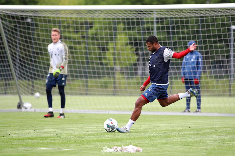 两名拜仁球员在保持安全距离的情况下进行传接球配合，绿草如茵的场地与球员们拉伸的身影构成一幅充满力量感的画面，无声中传递出团队间的默契。