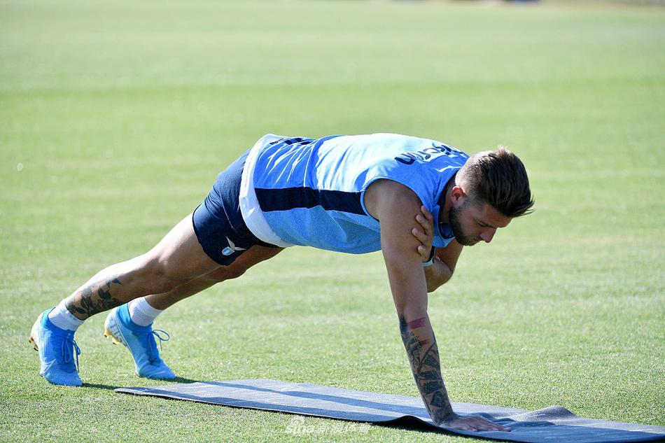 训练尾声，两名球员在场地边放松交流，远处的队旗迎风招展，定格了这个特殊赛季里为回归赛场而战的决心。