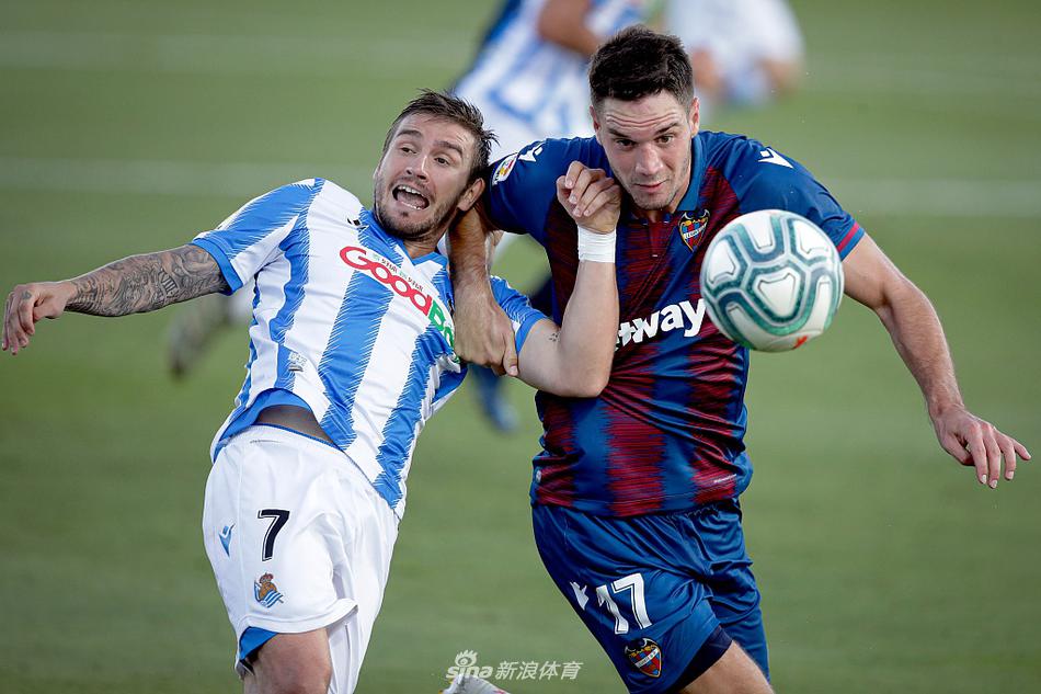 莱万特前锋莫拉莱斯进球后激情滑跪庆祝，他身后的队友罗奇纳手指着他奔跑的方向，脸上洋溢着同样激动的笑容，主场球迷在看台上挥舞着旗帜，场面热血沸腾。