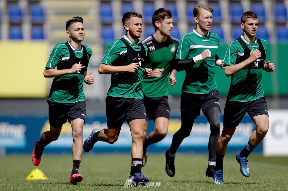 在抢圈热身中，一名球员轻巧地将球挑起，准备传给队友，脸上洋溢着轻松的笑容，旁边队友正全神贯注地准备接应。