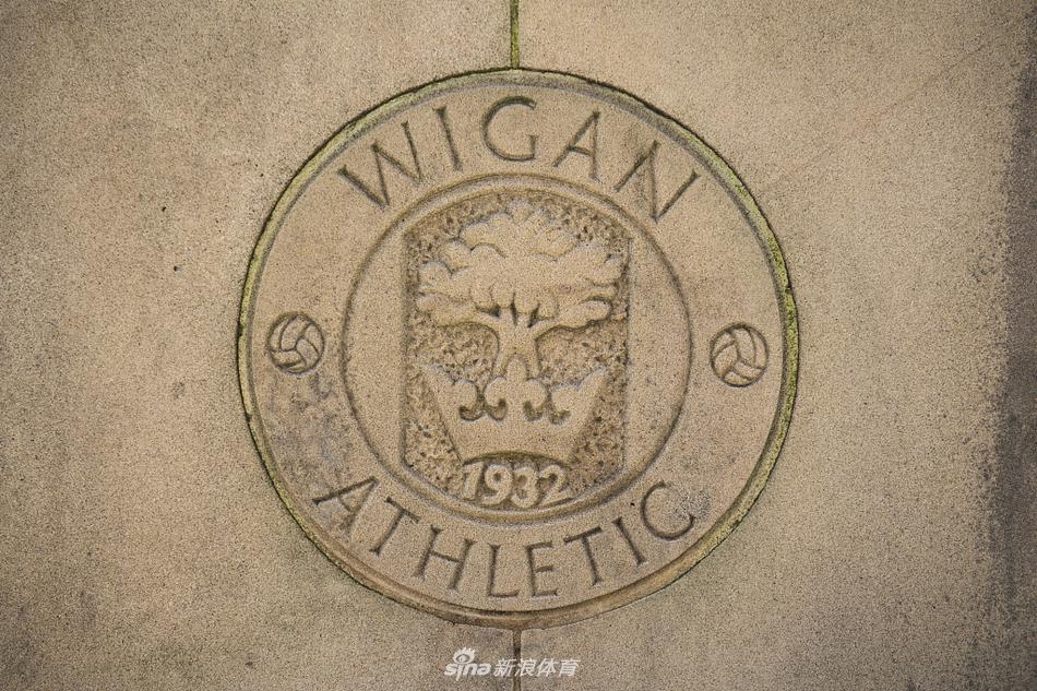 透过球场开阔的角落望向外部，远处的罗宾公园零售区建筑在夏日蓝天下清晰可见，球场巨大的照明灯柱高耸，仿佛在无声地预告着下一个比赛日的喧嚣。