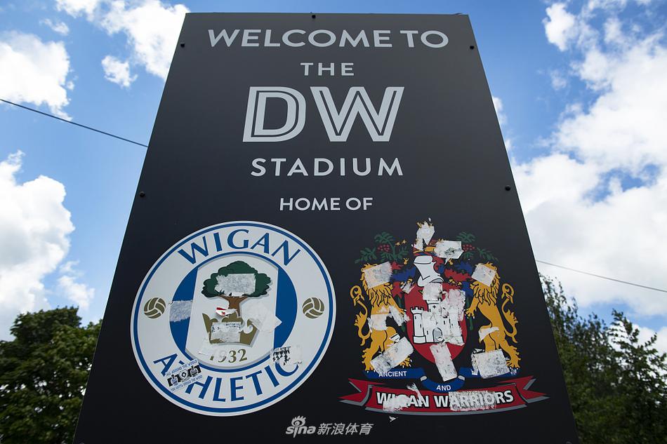 东看台巨大的电子记分牌静静矗立，屏幕黑屏，下方是“DW STADIUM”的字样，它像一位沉默的纪录者，等待着下一次为进球而亮起的辉煌时刻。