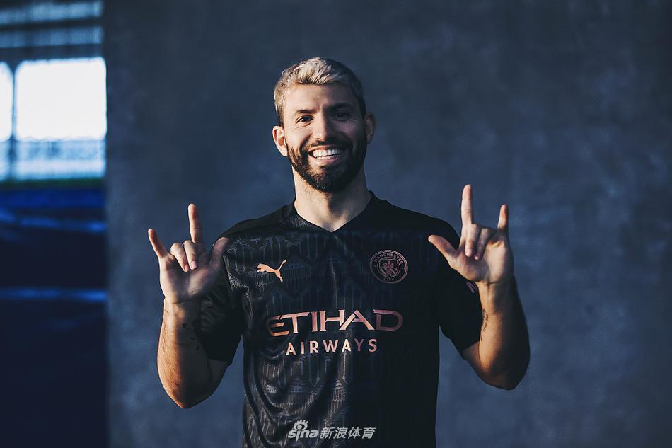 在柔和光影的笼罩下，斯特林身着全新的深蓝与黑交织的战袍，他的眼神望向远方，仿佛正凝视着新赛季的荣耀征途，背景的暗色调将球衣上精致的铜色细节衬托得如同夜空中闪烁的星辰。