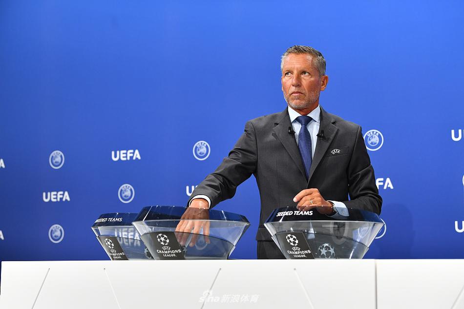 欧足联标志与背景板前的桌上，整齐摆放着印有各国足球协会旗帜的对阵卡，静待被抽取，象征着欧洲足球的团结与多元。