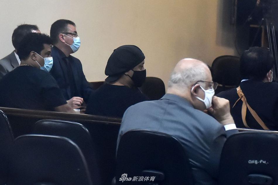 在酒店大堂门口，罗纳尔迪尼奥戴着一副眼镜，身穿印有图案的黑色T恤，正准备上车离开。他身后的自动门仿佛分隔了两个截然不同的世界，门外是通往巴西的自由之路。