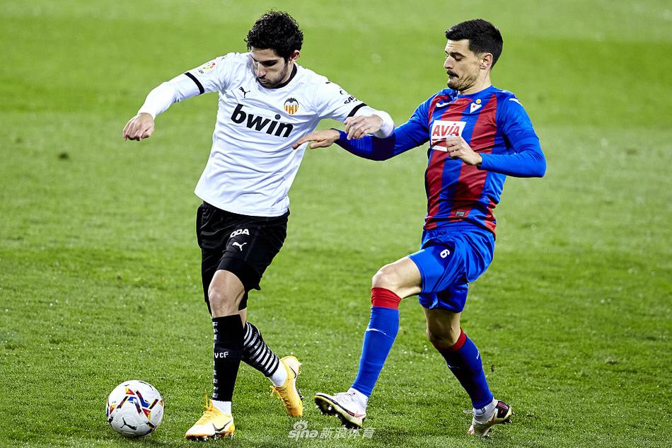 日本球星武藤嘉纪在禁区内完成射门瞬间，他身旁的瓦伦西亚防守球员飞身封堵，气氛紧张