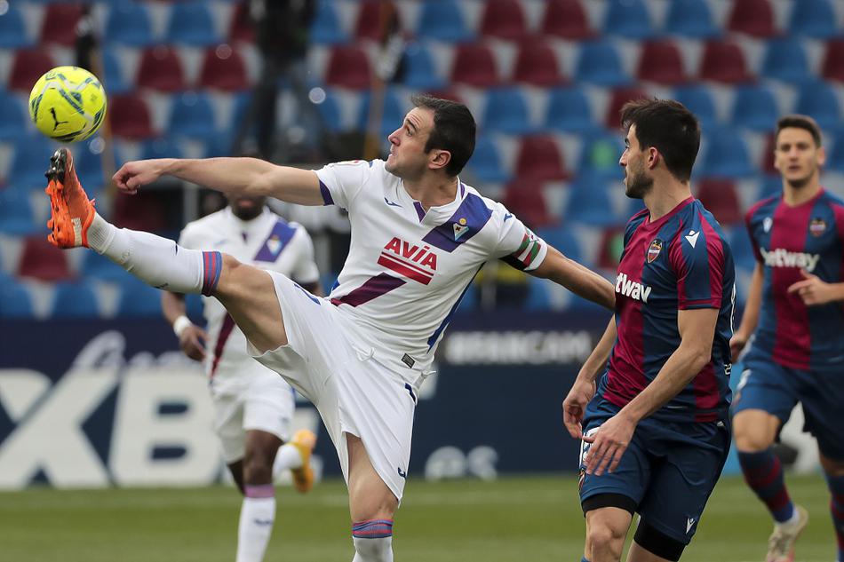 客队埃瓦尔的球员在终场哨响后难掩失落，一名球员低头叉腰站在场上，与不远处庆祝胜利的莱万特球员形成了鲜明而残酷的对比。