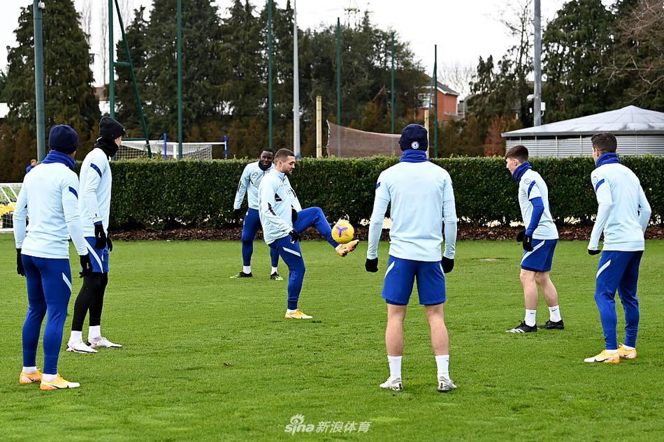 远景中的科巴姆训练基地，夕阳的余晖为球场披上了一层金色的外衣。球员们三三两两准备离场，他们的影子被拉得很长，仿佛预示着蓝军未来的道路虽长，但已铺满希望之光。