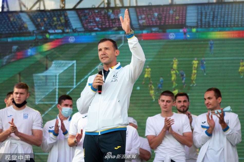 机场大厅内，一名身穿乌克兰球衣的小球迷骑在父亲肩头，努力探出身子与经过的球员击掌，球员弯下腰，满脸笑意地回应着这份纯真的崇拜。