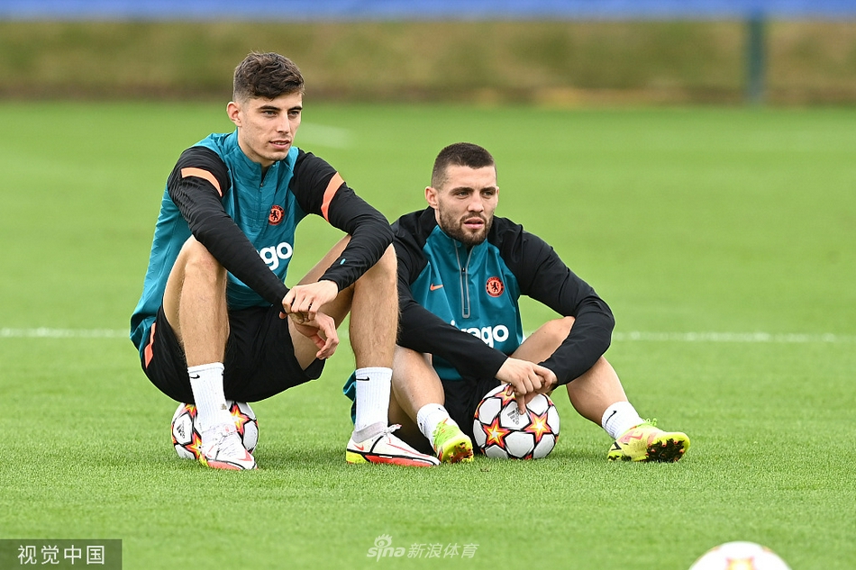 切尔西球员在训练场上全神贯注地听着教练的战术部署，阳光洒在科巴姆训练基地的草坪上，映照出卫冕冠军的从容与坚定。