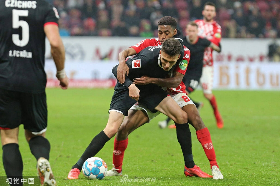 图片描述：美因茨球员在主场球迷的助威声中，与科隆队员展开激烈拼抢。