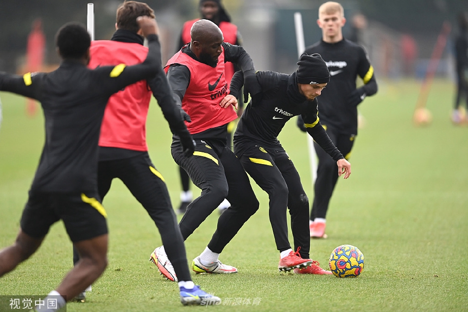 科巴姆训练基地全景，蓝天白云下，球员们分散在绿茵场上积极备战