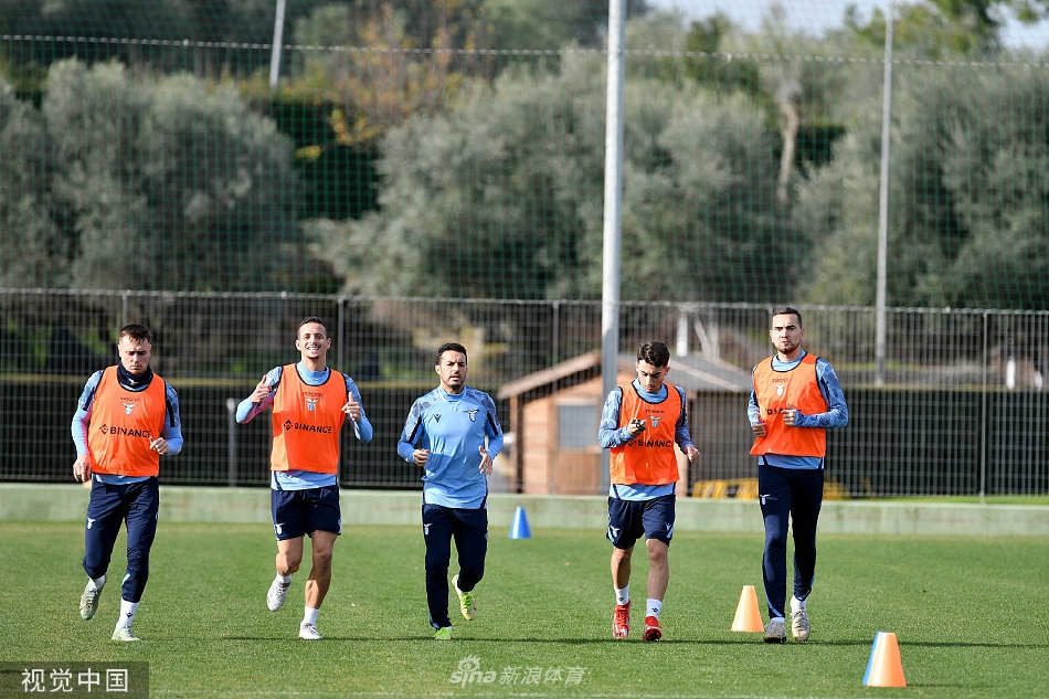 主教练萨里手持战术板神情专注，正在向围聚的球员们详细讲解比赛战术，场边的训练器材在冬日阳光下清晰可见。