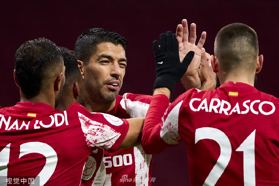 马竞前锋库尼亚在进球后张开双臂，与队友卡拉斯科激情庆祝，背景是略显沮丧的马哈达翁达闪电后卫。