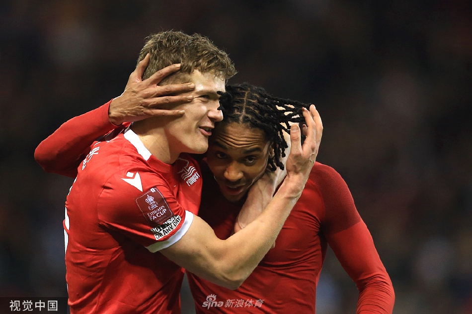 诺丁汉森林球员在终场哨响后激动地拥抱庆祝，背后是失望离场的阿森纳球员身影