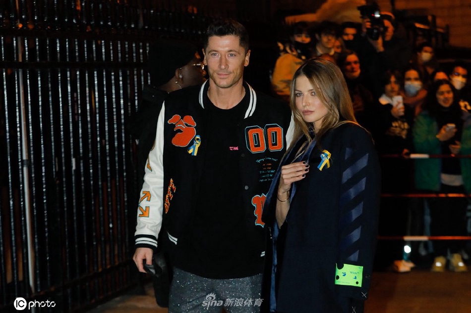 莱万低头与妻子安娜温柔对视，安娜眼中含笑，两人在喧闹的秀场外仿佛置身于只属于彼此的静谧空间。