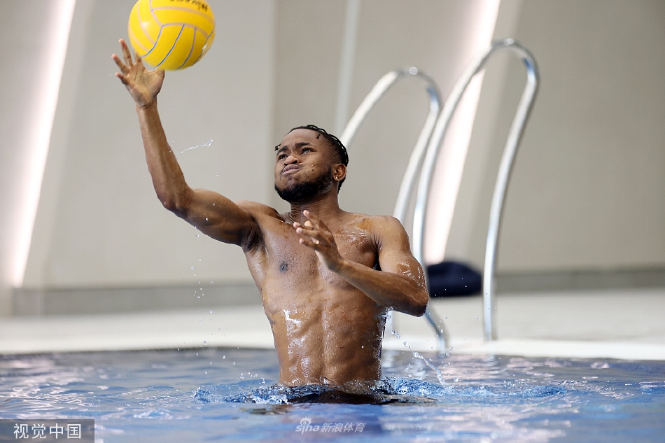 两名球员在水中协同防守，他们目光紧盯水球，身体对抗间激起了巨大的水浪。