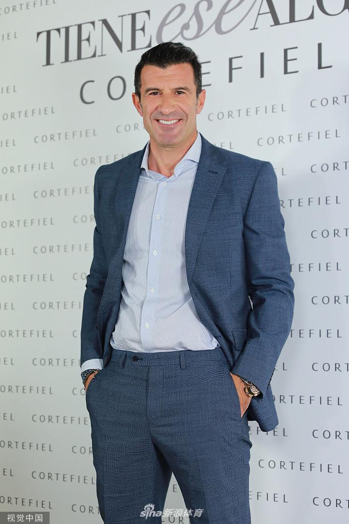 活动中的菲戈眉头微蹙，似乎在认真倾听旁人的话语，身旁的妻子海伦则大方地面对镜头，展现出职业模特的镜头感。