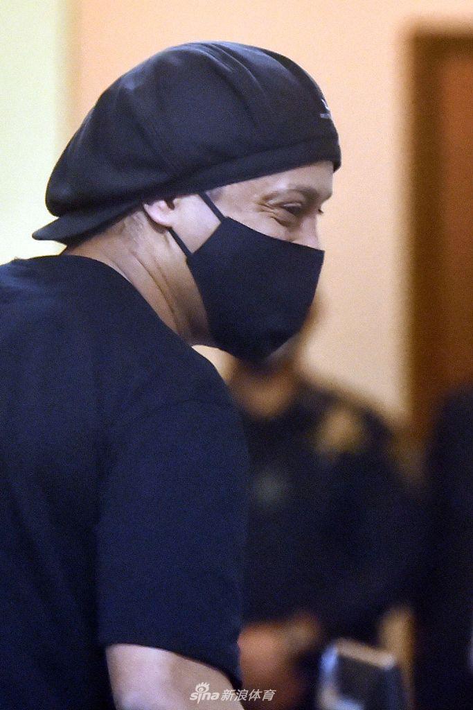 画面中，罗纳尔迪尼奥正弯腰为一位身着制服的警察签名。即使在人生低谷，他依然保持着亲和的魅力，用足球带给他的魔力，消融着铁窗内外的界限。