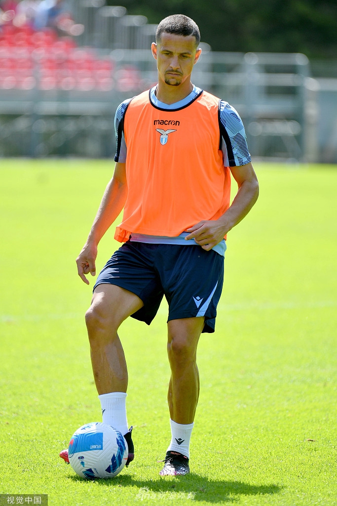 一名拉齐奥球员正在进行个人技术训练，他全神贯注地控制着皮球，远处的队友和教练组构成了新赛季备战期的忙碌背景。