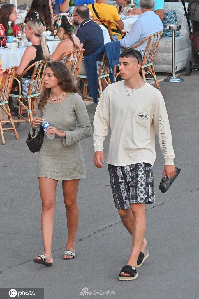 两人在游艇上惬意放松，背景是停泊着众多帆船的圣特罗佩港湾