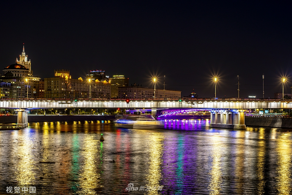 夜色下的莫斯科街头，以标志性建筑为背景，一块巨大的电子屏幕正滚动播放着沙滩足球世界杯的预热宣传片，绚丽的画面与城市的璀璨灯火交织在一起。