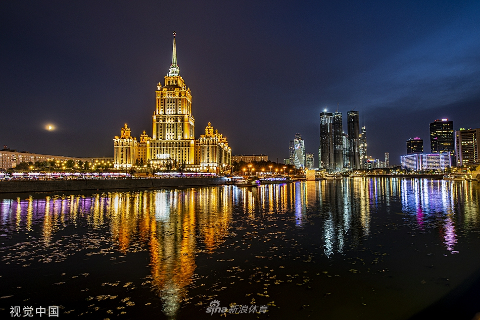 卢日尼基体育场外的沙滩足球世界杯官方看板被灯光照亮，醒目的赛事Logo与“俄罗斯2021”字样，向每一位过往的行人宣告着这场顶级沙足盛宴即将在这座城市拉开帷幕。