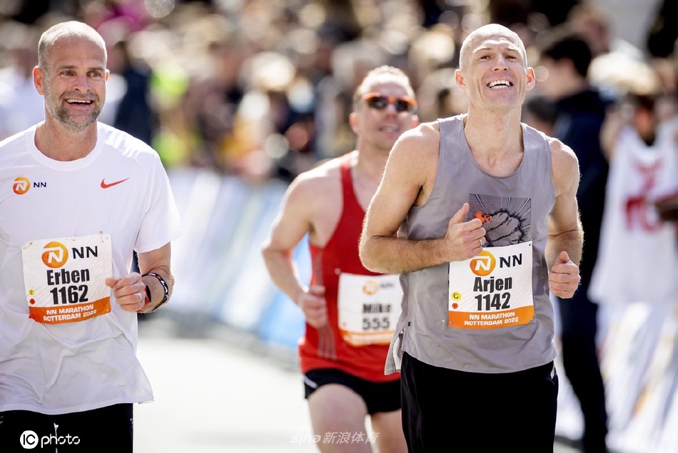 冲线时刻罗本张开双臂拥抱胜利，背后是鹿特丹标志性的现代建筑与欢呼人群