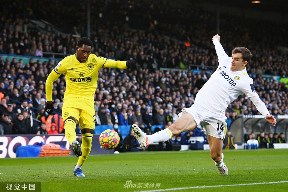 利兹联与布伦特福德球员在灯火通明的埃兰路球场上激烈拼抢，一次关键的争顶瞬间定格了比赛的紧张氛围