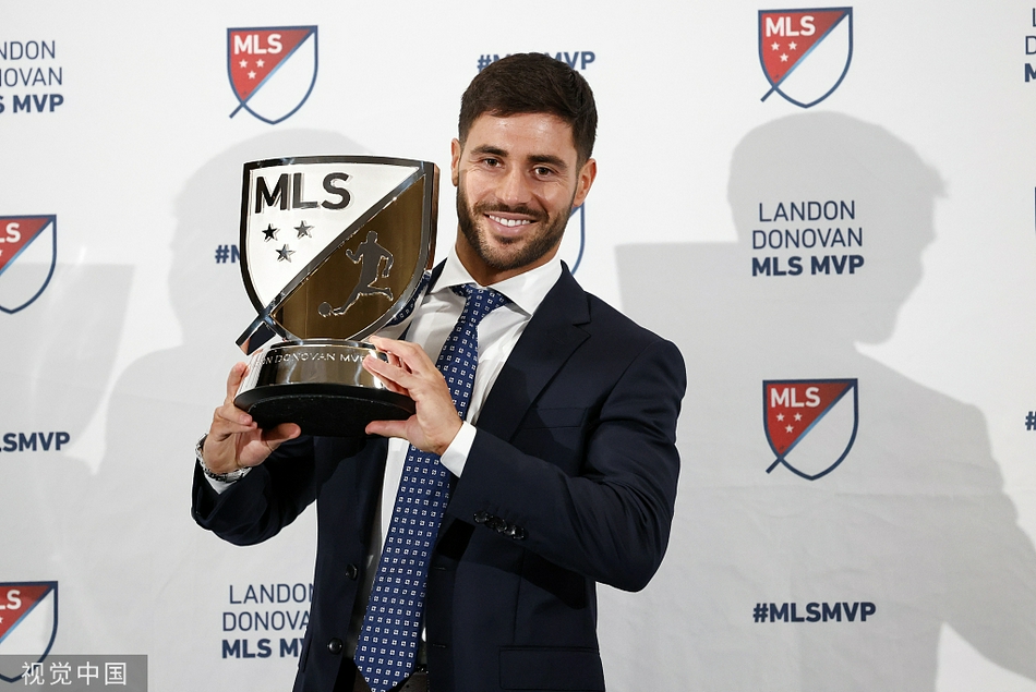 卡莱斯·希尔身着笔挺西装，手捧兰登·多诺万MVP奖杯，脸上洋溢着难以抑制的激动与自豪之情。