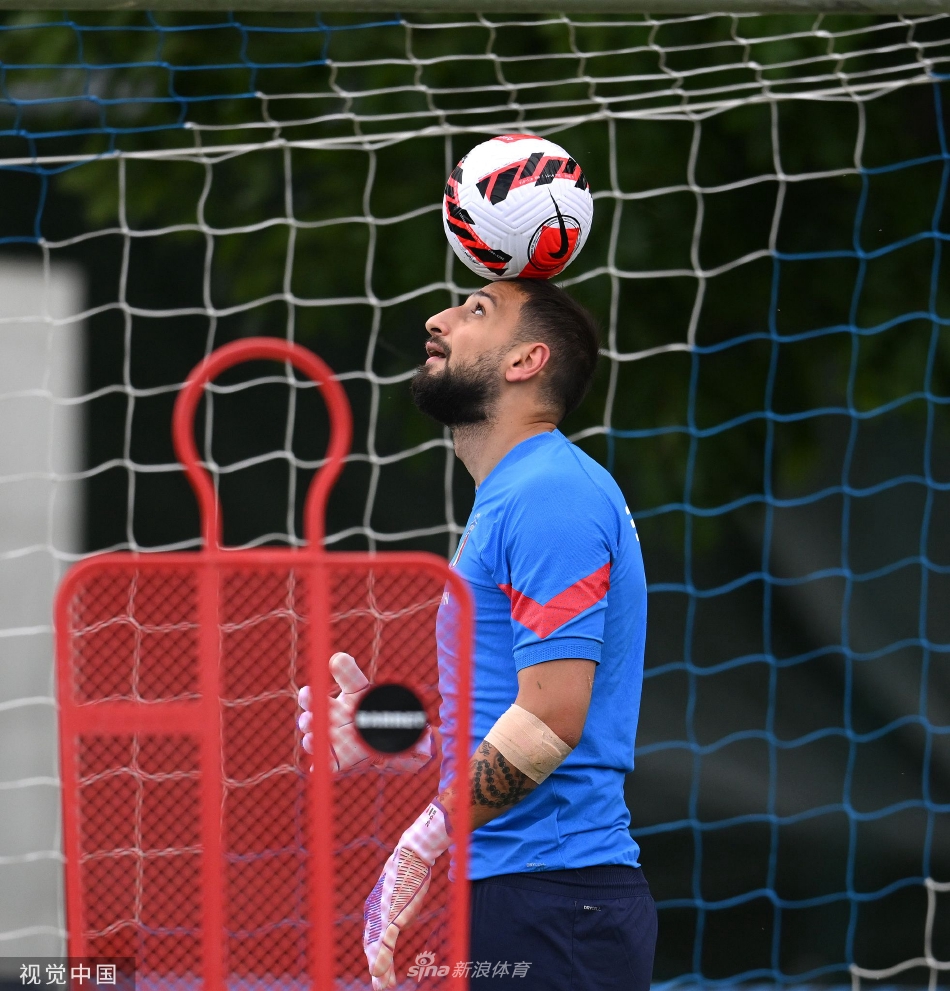 守门员教练正在指导多纳鲁马进行地面扑救训练，多纳鲁马身体极度舒展，如同一只猎豹扑向目标，手套即将触碰到滚向死角的皮球，瞬间凝聚了力量与柔韧之美。