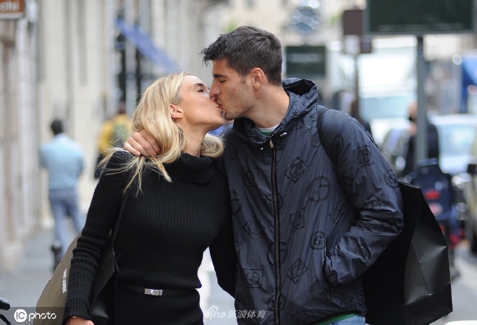 莫拉塔与爱丽丝在米兰街头相视而笑，阳光洒在他们身上，爱丽丝手中的购物袋也掩不住两人之间的浓情蜜意。