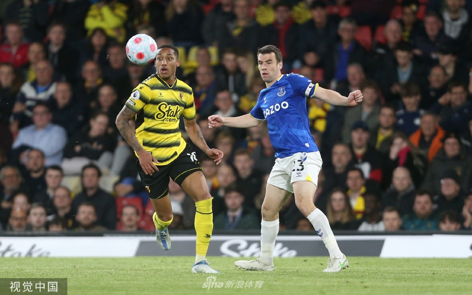 双方球员在中场展开激烈空中争顶，球衣在灯光下与草皮形成鲜明对比