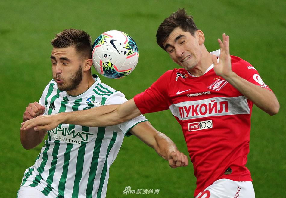 莫斯科斯巴达克球员在主场奥特克里蒂耶竞技场激烈拼抢，红色的球衣在夜色灯光下格外醒目，对手格罗兹尼特里克的防守球员贴身紧逼，展现了俄超联赛的高强度对抗。