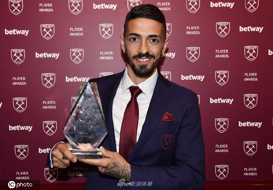 英格兰中场德克兰·赖斯手捧赛季最佳球员奖杯，脸上洋溢着自豪与喜悦的笑容，身后是闪耀的俱乐部标志。